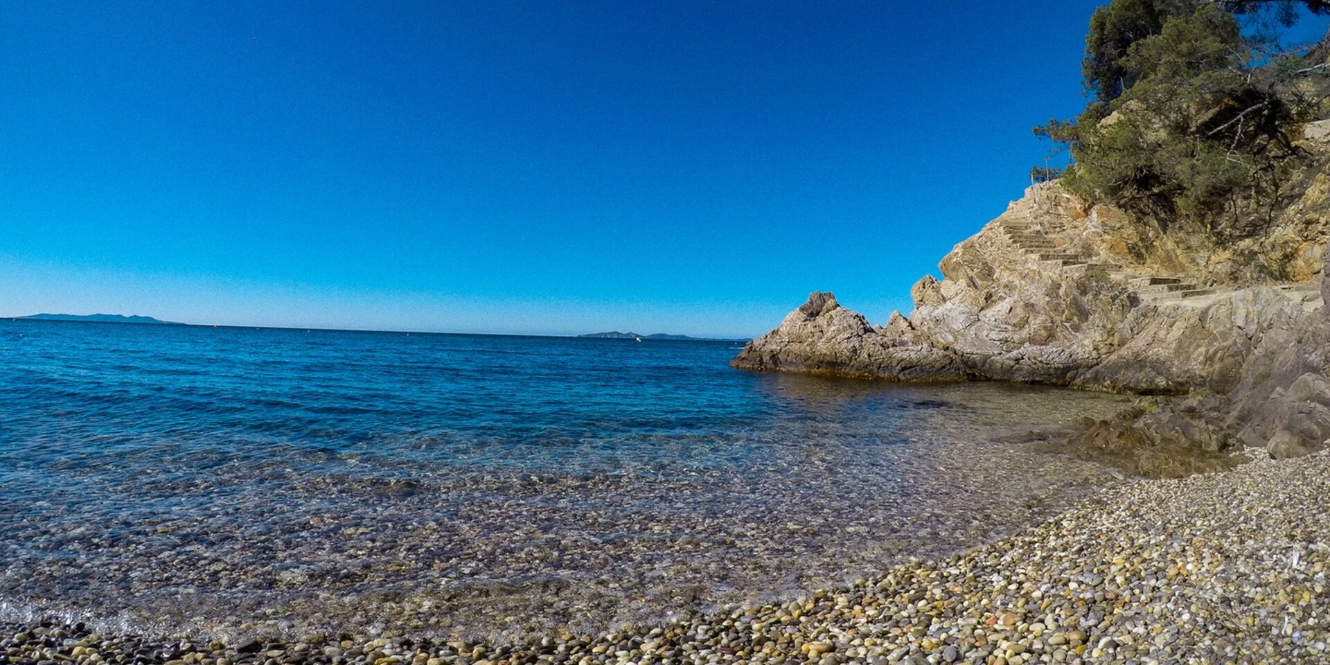 Ein Strand mit Sand und Kieselsteinen in Bormes